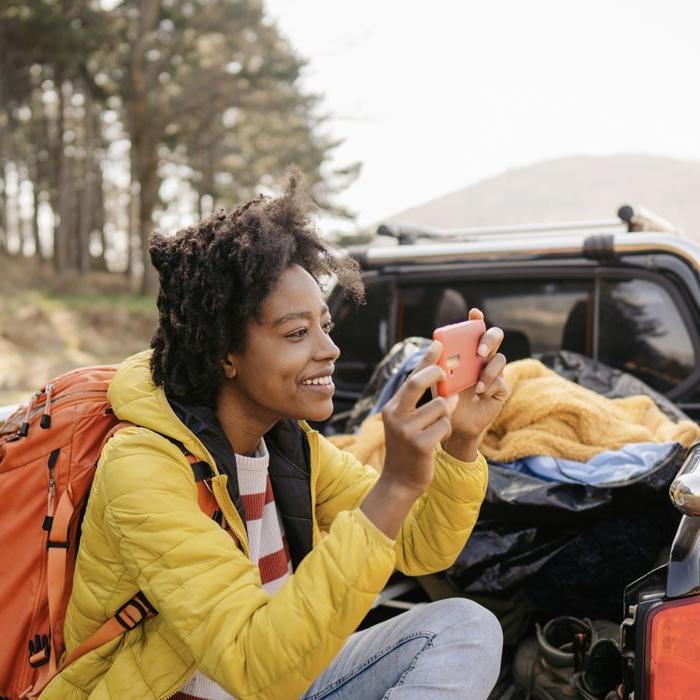 一个露营者用她的手机在一辆装满露营装备的皮卡车后面拍了一张照片.